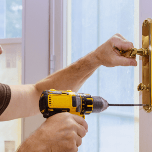 commercial locksmith Kingsport - The Benefits of Installing Deadbolts - a brass doorknob and deadbolt set being installed using a drill