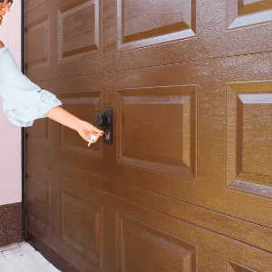 Best garage door lock - a woman's hand turning a key to a garage door lock